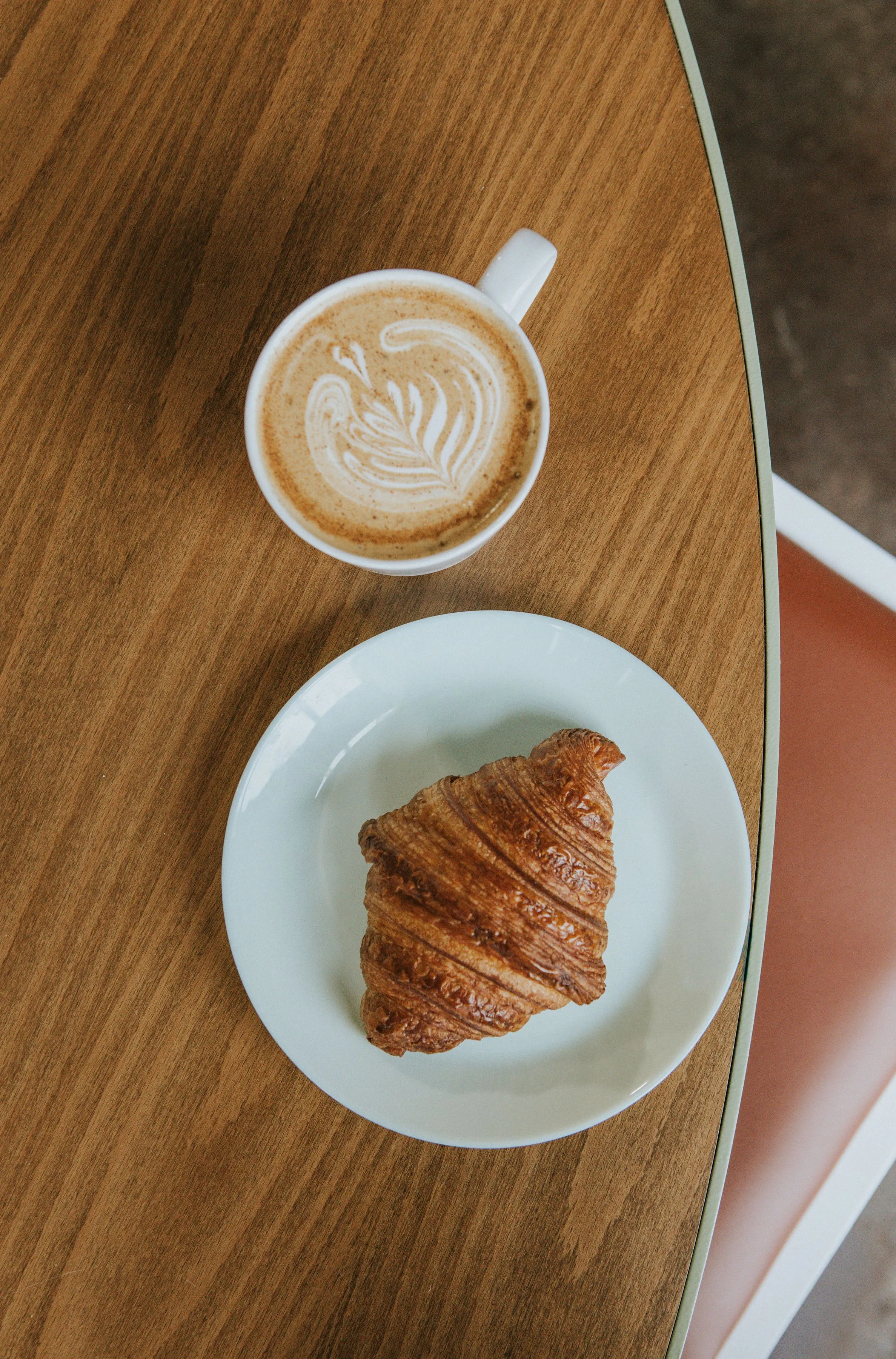 A top view of a table with a coffee and a croissant
