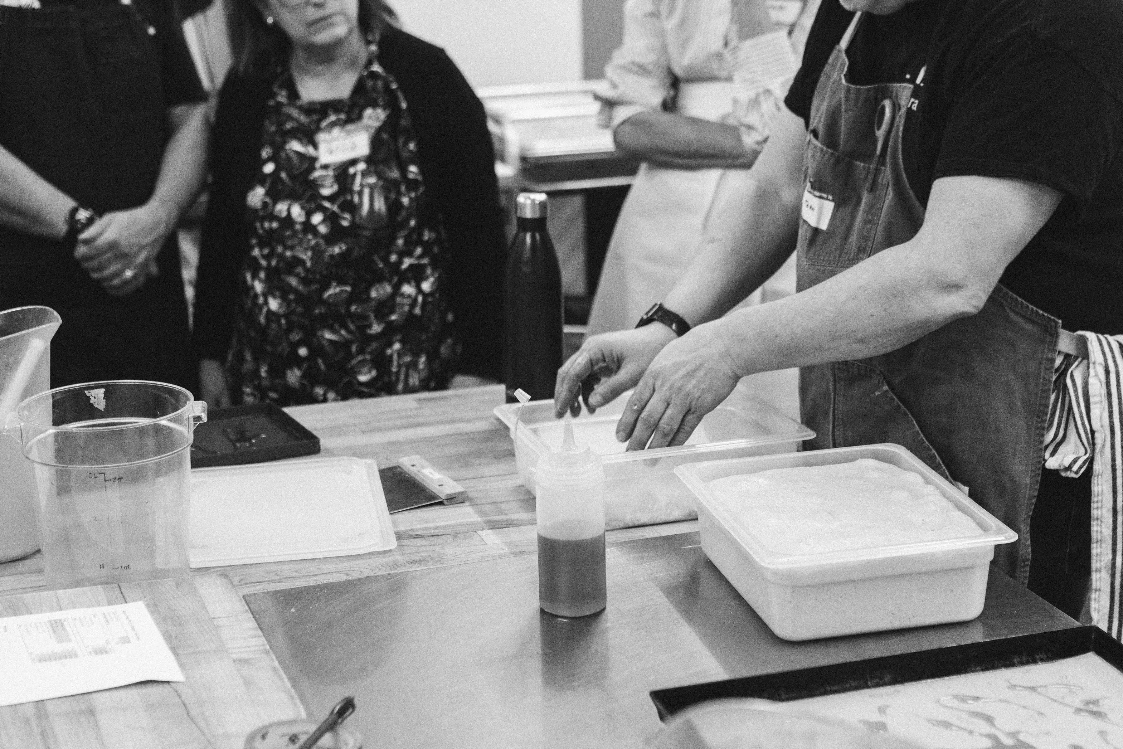 A workshop teacher folding dough while participants watch