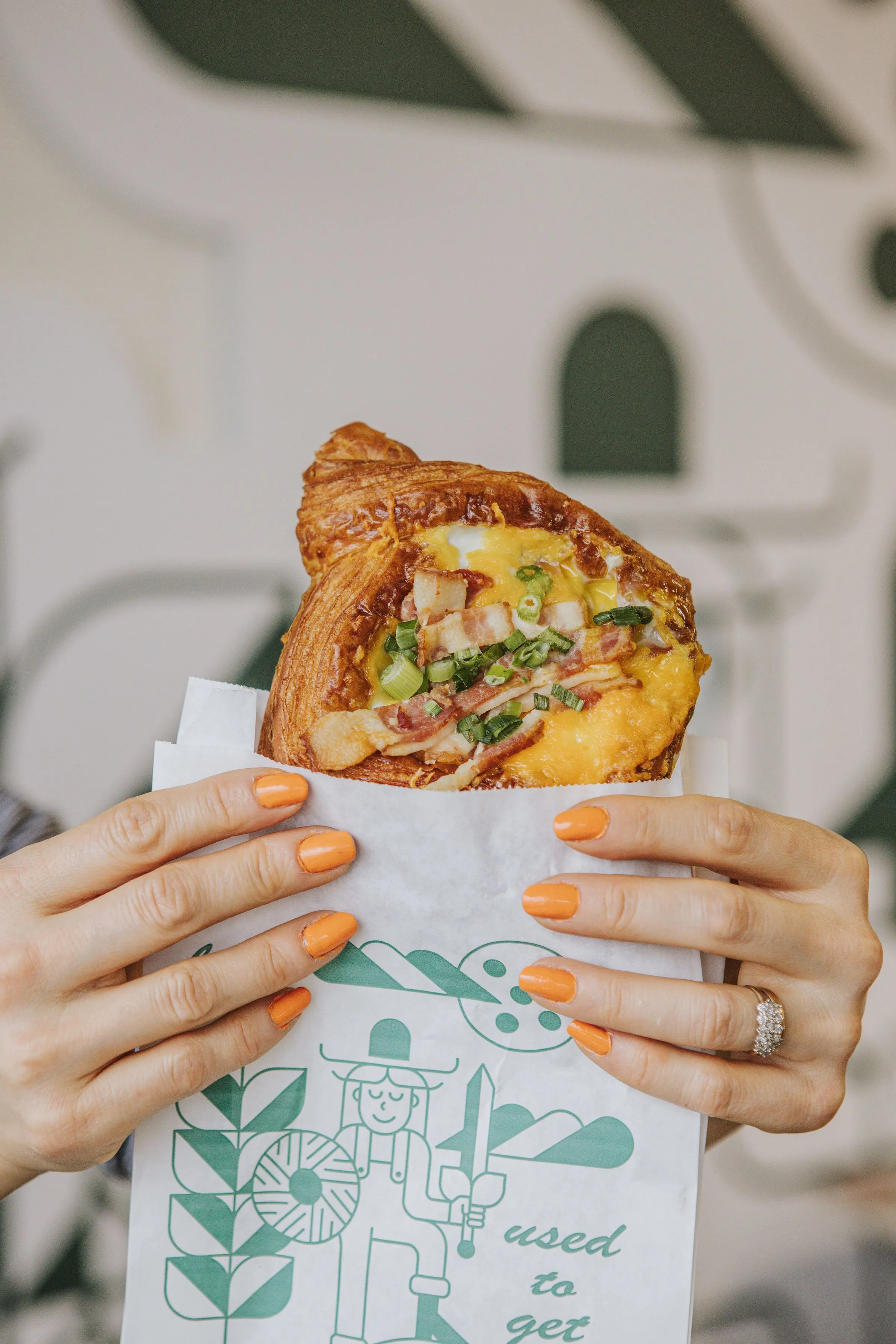 A pair of hands holding a pastry bag with a breakfast danish popping out the top